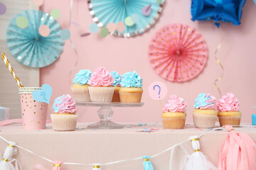 Delicious cupcakes with question mark and decorations on table against pink background. Gender...