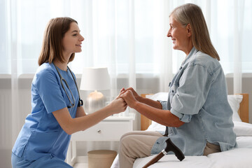 Smiling healthcare worker supporting senior patient indoors