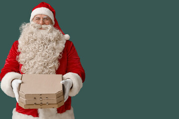 Santa Claus with boxes of tasty pizza on green background