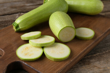Board with fresh zucchinis on wooden table, closeup