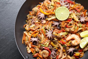 Stir-fry sea food in wok on grey textured table, top view