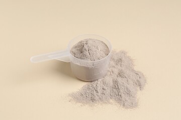 Protein powder and scoop on beige background