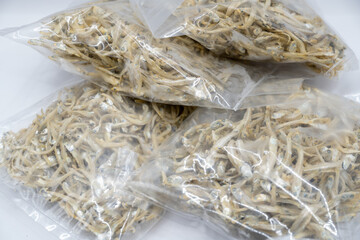 This close-up image showcases a textured mound of dried anchovies, their silvery bodies intertwined...