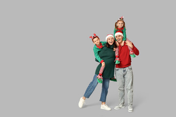 Happy family in Christmas clothes on grey background
