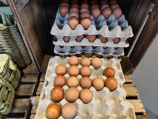 Stacked cardboard egg tray boxes with fresh eggs lie on a supermarket shelf to be sold