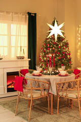 Interior of festive room with Christmas tree, decorations, fireplace and served dining table at evening