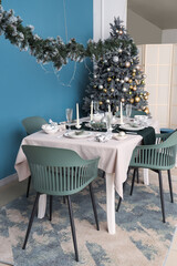 Interior of festive room with Christmas tree, decorations and served dining table