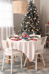 Interior of festive room with Christmas tree, decorations and served dining table