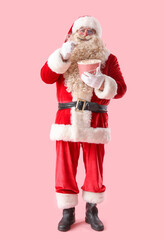 Santa Claus with tasty popcorn on pink background