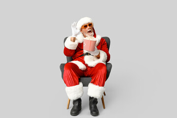 Santa Claus in 3D glasses with bucket of tasty popcorn on grey background