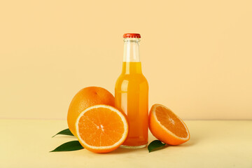 Bottle of fresh orange juice and leaves on color background