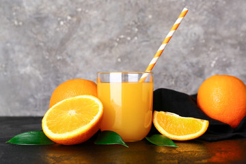 Glass of fresh orange juice and leaves on black table