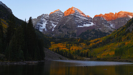 Sunrise hits the snow capped mountain peaks of Maroon Bells in Aspen, Colorado USA