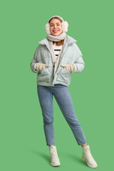 Beautiful young happy woman in warm winter clothes on green background