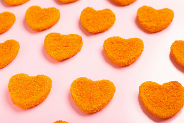 Tasty nuggets in shape of heart on pink background. Valentine's Day celebration