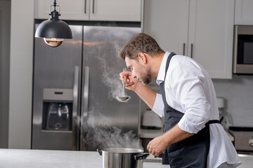 chef stirring a pot of aromatic soup with ladle. Chef cook in uniform cooking soup in the big...