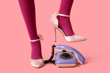 Beautiful young woman with retro telephone on pink background