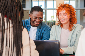 Two Multiracial Teenage Students Smiling While Learning the Lesson and Preparing for an Exam in the University Campus Library. Young Classmates Reading Notes Doing High School Homework Project