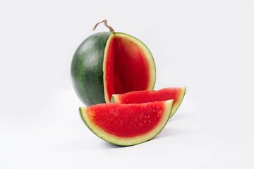Whole watermelon and seeded slices seen front and top on a white background. Watermelon slices are red, seedy and juicy.