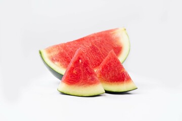 Whole watermelon and seeded slices seen front and top on a white background. Watermelon slices are red, seedy and juicy.