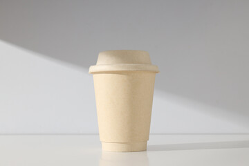 A paper cup with a lid on a light background
