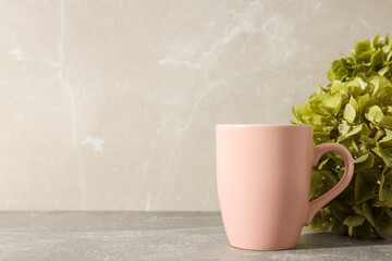 A pink cup with green hydrangeas in a vase