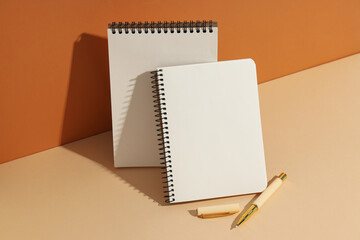Open notebooks stand with pens on a light background