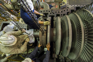 Technicians of a geothermoelectric plant performing maintenance on the electric generator as part of annual scheduled maintenance. disassembling turbine rotor. Top view