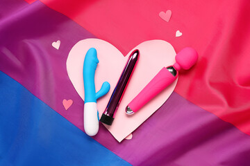 Vibrators with paper hearts on bisexual pride flag. Valentine's Day celebration