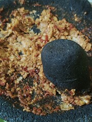 Fototapeta premium photo of pestle after finishing pressing tempeh and chili on the mortar
