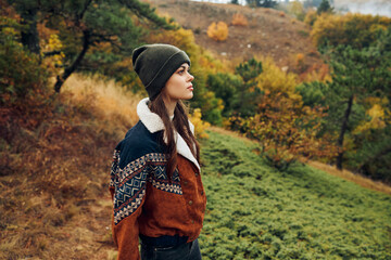 A young woman enjoying the peaceful beauty of an autumn forest landscape with mountains in...