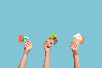 Female hands with different condoms on color background