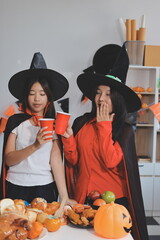 friendship, holiday and people concept - group of happy smiling friends in halloween costumes of vampire, devil, witch and cheetah at home party