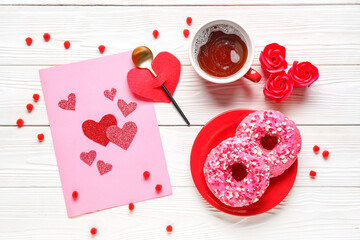 Cup of tea with donuts, festive card and decor on white wooden background. Valentine's Day celebration