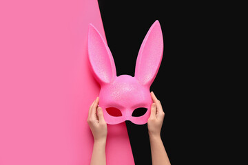 Female hands with pink bunny mask on color background