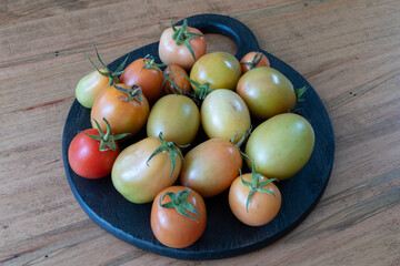 Green home grown tomatoes ripening on a wooden board and table.