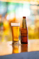 Close-up of a cold beer bottle and glass on a bar counter with a blurred background, creating a vibrant and inviting atmosphere, at Museo Larco in Lima, Peru.