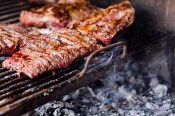 Roasted meat on the grill. Barbeque, bbq meat cooking. Traditional Asado of Argentina, Paraguay and Uruguay. Horizontal format.