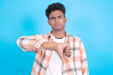 Upset Young Asian Man in Casual Clothes Showing Thumb Down Isolated on Blue Background