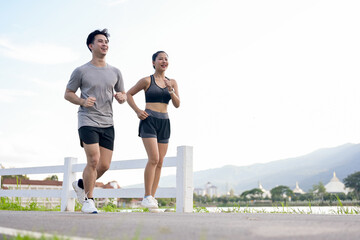 An active, sporty Asian couple in sportswear is jogging or running together in the park.