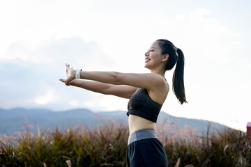 A sporty Asian girl in sportswear is stretching her arms, warming up before her morning run.