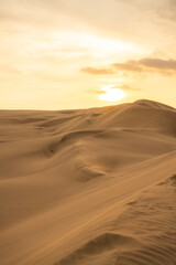 Breathtaking golden sunset over the sand dunes in Huacachina, Ica, Peru, creating a serene desert...