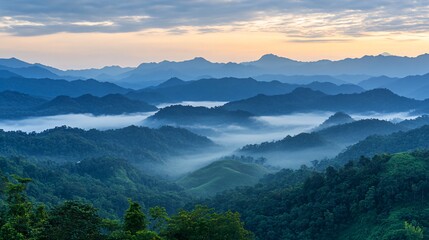 Obraz premium Serene sunrise over misty mountain ranges with layers of blue clouds and lush green valleys.