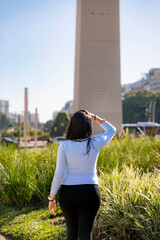 Unrecognizable young Latina woman smiling in front of the iconic Obelisk in Buenos Aires,...