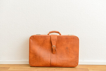 Brown retro leather suitcase on floor in room