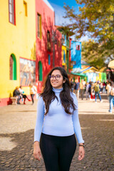Young Latina woman walking in front of the brightly colored houses in Caminito, La Boca, Buenos...