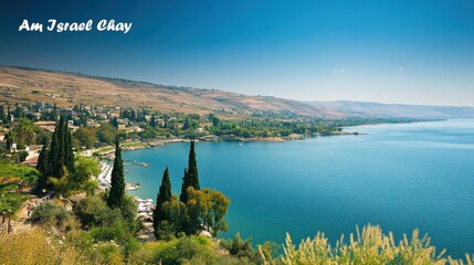 Beautiful view of the Sea of Galilee with distant hills under a clear blue sky, featuring "Am Israel Chay" text.
