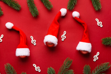 Composition with Santa hats, fir branches and violin clefs on red background