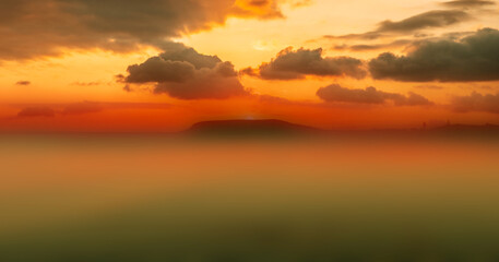 Colorful golden sunset sky with fog mist effect over the ocean background. Dramatic beautiful nature light sky in background.