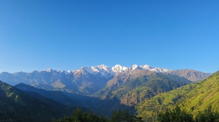 photo of the majestic beauty of a towering mountain range, with rugged peaks covered in snow, lush green valleys below, and a clear blue sky, creating a breathtaking natural landscape